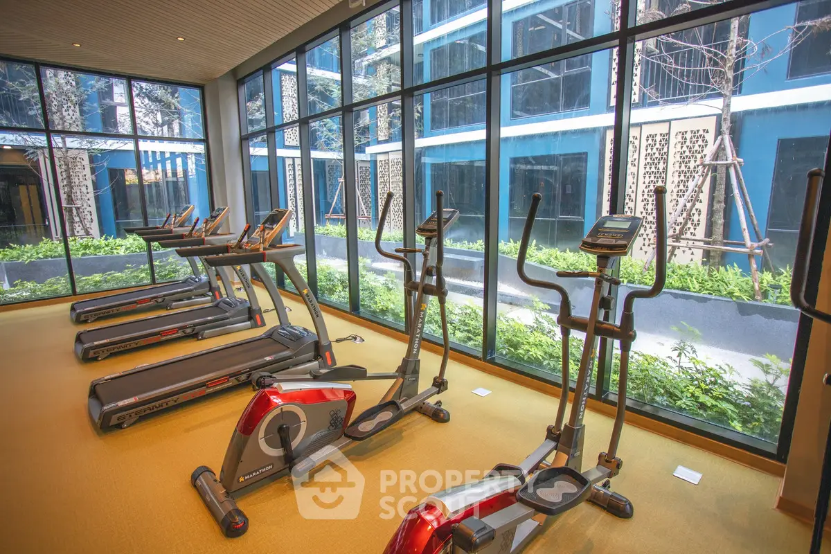 Modern gym with state-of-the-art equipment and garden view in luxury apartment complex.