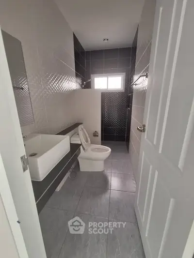 Modern bathroom with sleek design and contemporary fixtures, featuring a stylish sink and toilet.