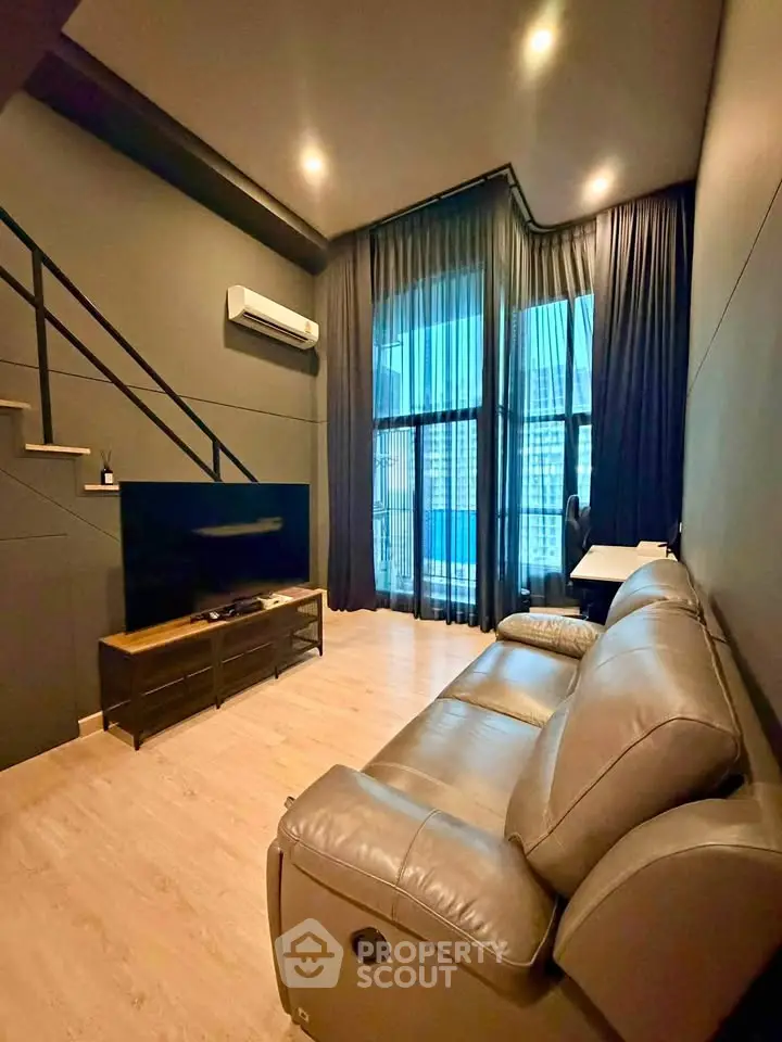 Modern living room with high ceilings, large windows, and stylish furniture in a contemporary apartment.