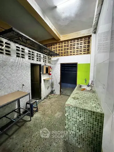 Spacious industrial-style kitchen with tiled countertops and open shelving, perfect for culinary creativity.