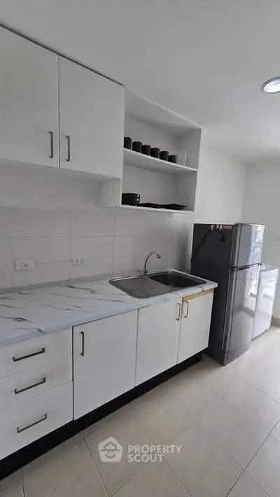 Modern kitchen with sleek cabinets and stainless steel fridge in a bright apartment.
