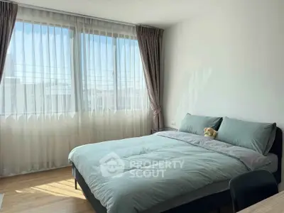 Bright bedroom with large windows and cozy bedding, perfect for relaxation.