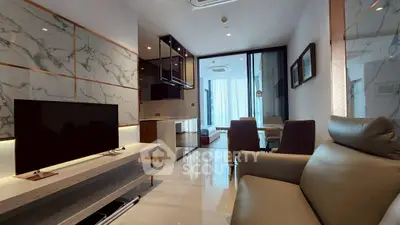 Modern living room with sleek design and marble accents, featuring a cozy seating area and a flat-screen TV.