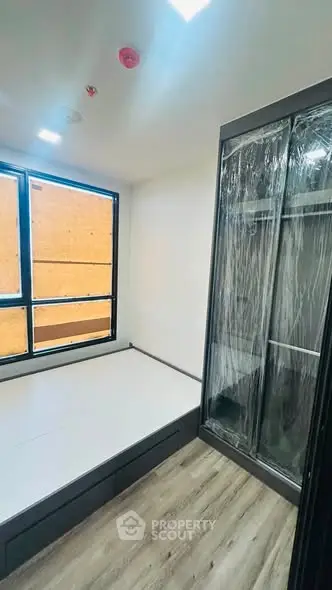 Modern bedroom with large window and sleek wardrobe in a contemporary apartment.