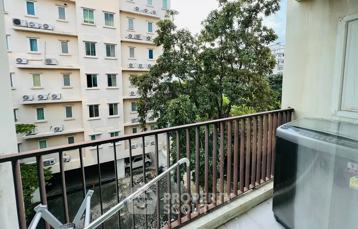 Charming balcony view overlooking lush greenery and modern building facade, perfect for urban living.