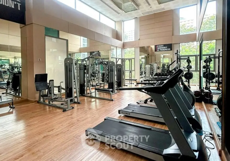 Spacious modern gym with state-of-the-art fitness equipment and large windows for natural light.