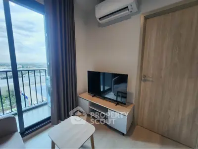 Modern living room with balcony view, featuring sleek TV setup and air conditioning.