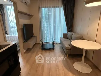 Modern living room with sleek furniture and large window view in urban apartment.
