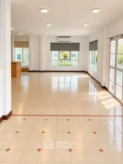 Spacious open-plan living room with large windows and tiled flooring