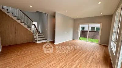 Spacious modern living room with wooden flooring and large windows for natural light.