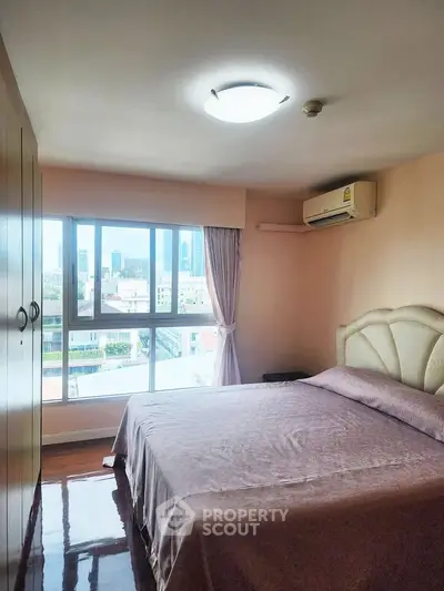Cozy bedroom with large window offering city views and ample natural light.