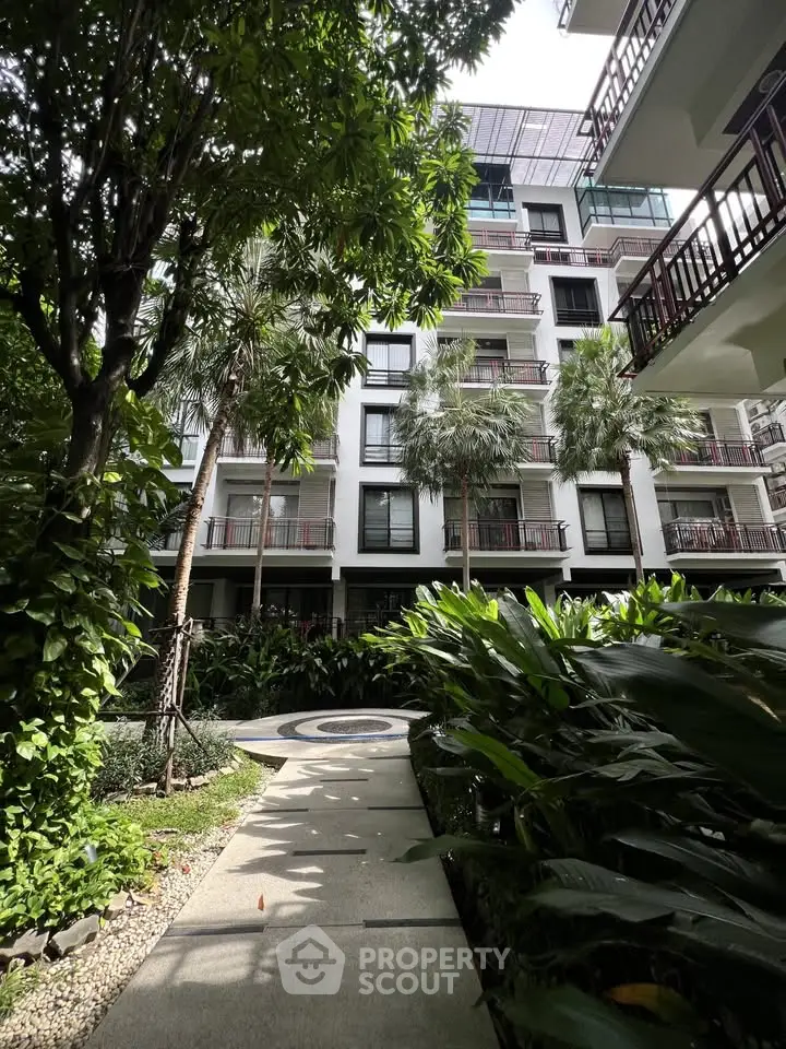 Modern apartment building with lush garden and pathway in urban setting
