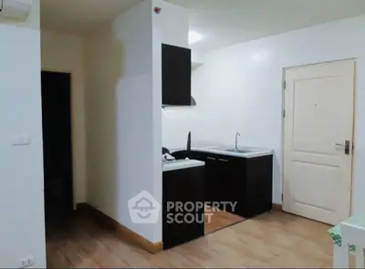 Compact kitchen with dark cabinets and white walls in modern apartment