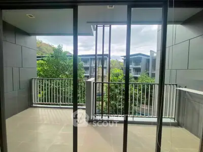 Spacious balcony with modern railing and scenic view of lush greenery and contemporary buildings.