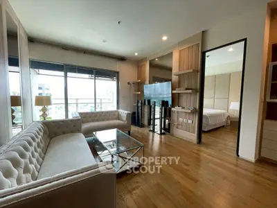 Luxurious living room with elegant furniture and city view, connected to a cozy bedroom.
