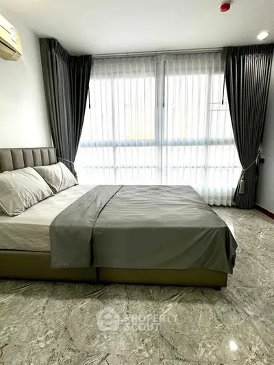 Spacious bedroom with elegant marble flooring and large window for natural light.