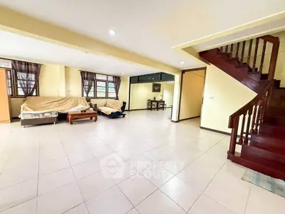 Spacious living room with tiled floor and wooden staircase in modern home
