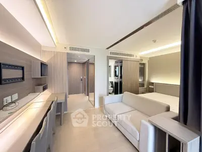 Modern studio apartment with sleek design and neutral tones, featuring a cozy sofa and built-in desk area.