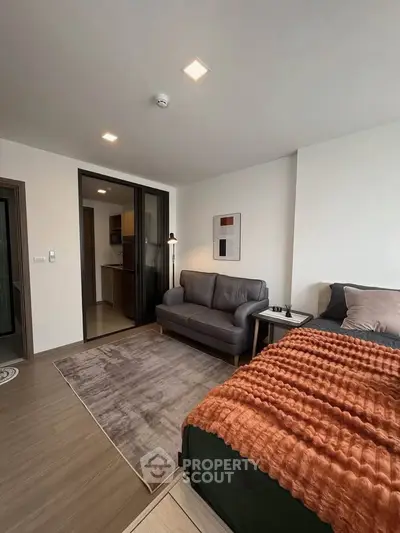 Modern bedroom with cozy bed, stylish sofa, and elegant decor in a contemporary apartment.