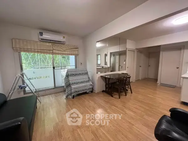 Spacious living room with wooden flooring and large window, perfect for modern living.