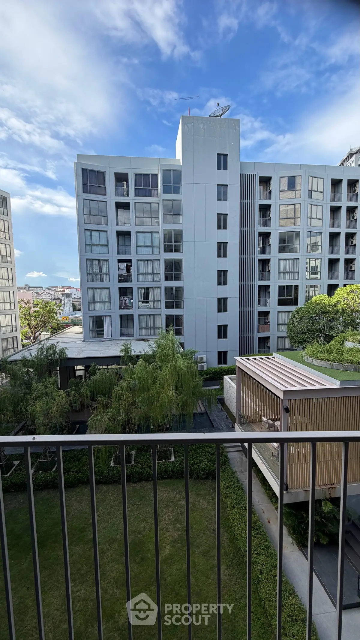 Modern apartment building with lush garden view and clear blue sky.