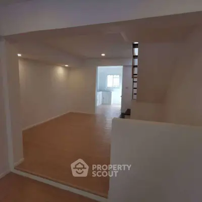 Spacious open-plan living area with modern wooden flooring and recessed lighting.