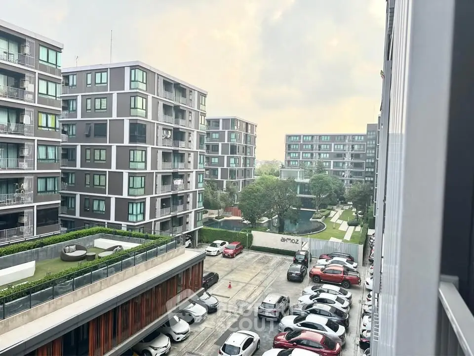 Modern apartment complex with ample parking and lush greenery, offering a serene urban living experience.