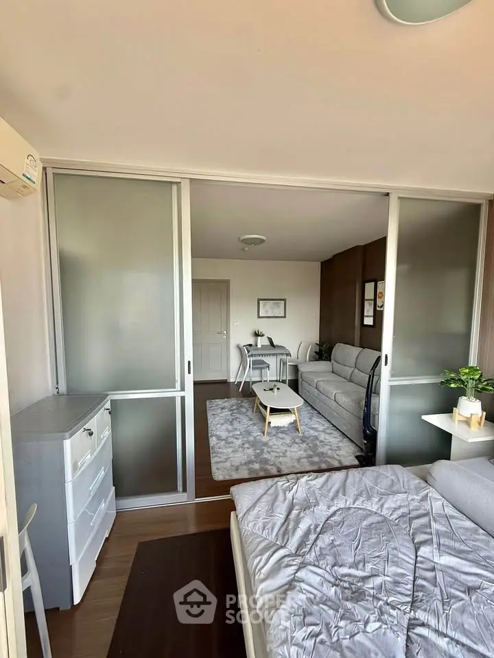 Modern open-plan living room with sliding glass doors and cozy bedroom area.