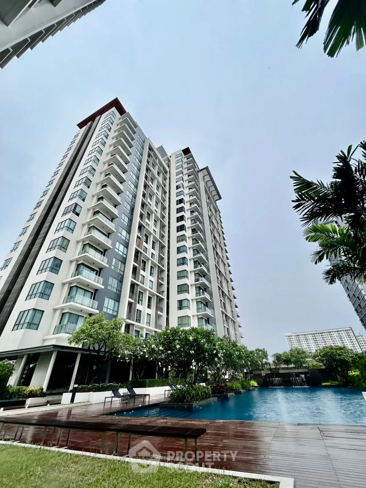 Luxurious high-rise building with pool and lush greenery, perfect for modern urban living.
