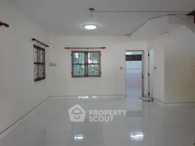 Spacious empty room with tiled floor and staircase, ideal for customization.