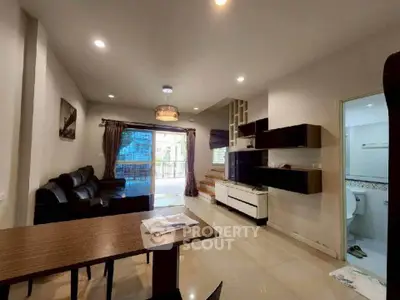 Spacious living room with modern decor and open layout, featuring a cozy seating area and natural light.