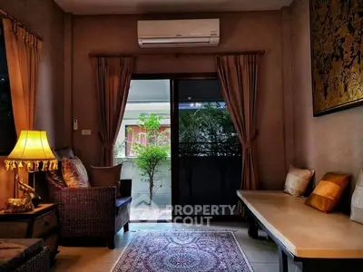 Cozy living room with elegant decor and garden view through sliding glass doors.