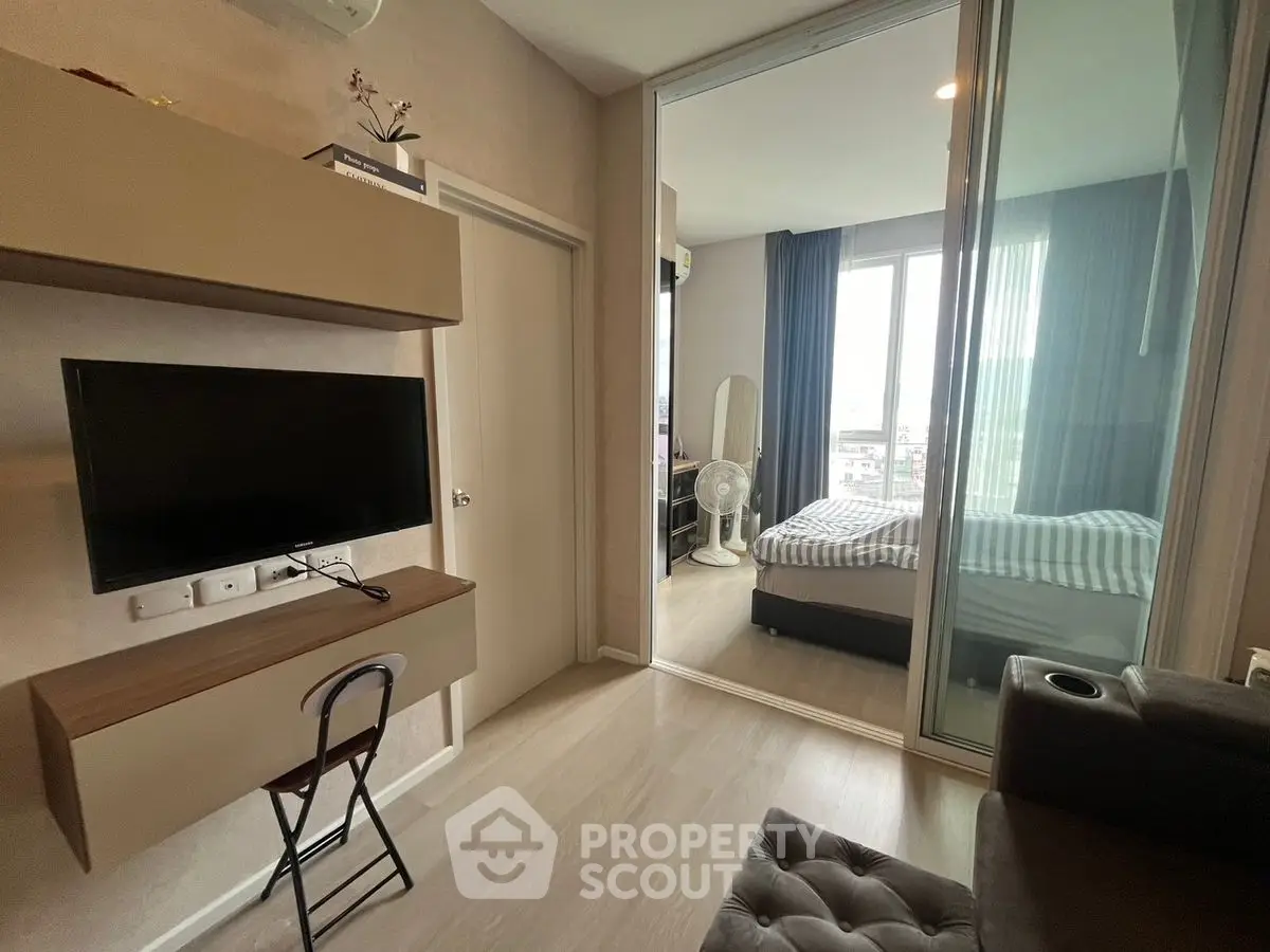 Modern apartment interior with cozy living room and stylish bedroom separated by glass wall.