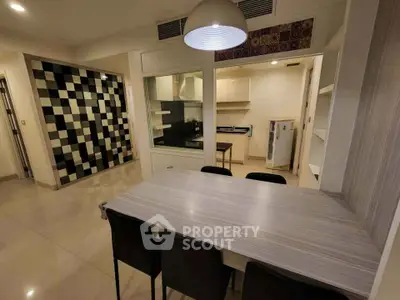 Modern kitchen with dining area featuring sleek cabinetry and stylish black and white tile accents.