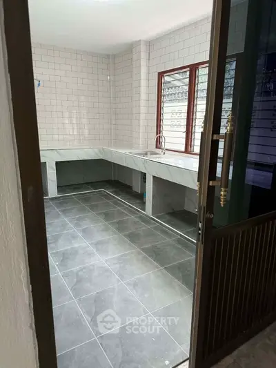 Modern kitchen with sleek tile flooring and large window for natural light