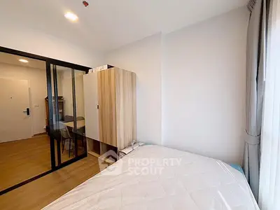Modern bedroom with sliding glass doors and wooden wardrobe in a cozy apartment.