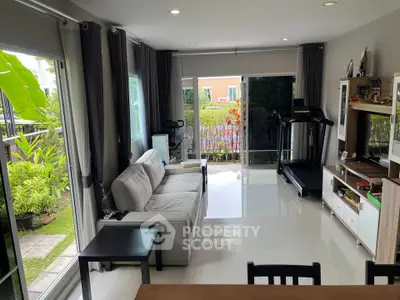 Spacious living room with modern decor and garden view, featuring a treadmill and entertainment unit.