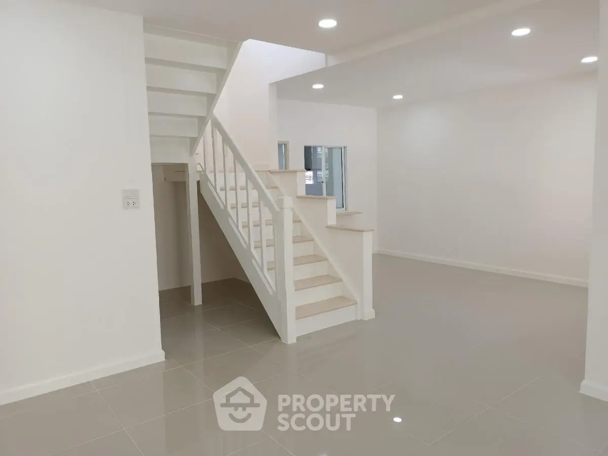 Spacious modern living room with sleek staircase and glossy tiled floor