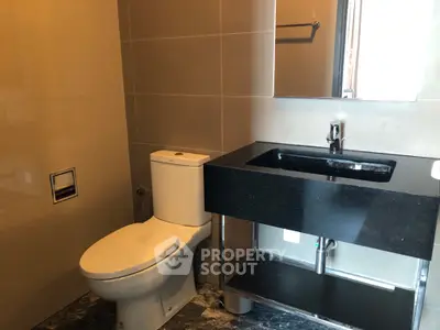 Modern bathroom with sleek black sink and marble flooring in a contemporary home.