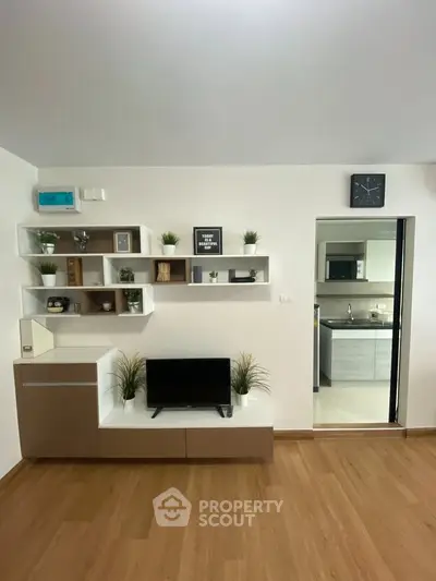 Modern living room with stylish shelving and view into a sleek kitchen