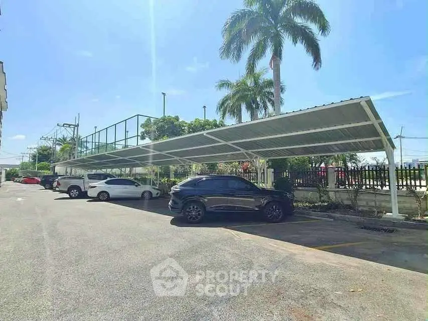 Spacious parking area with covered carports and palm trees in a sunny setting.