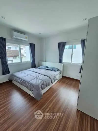 Spacious bedroom with modern decor and large windows for natural light