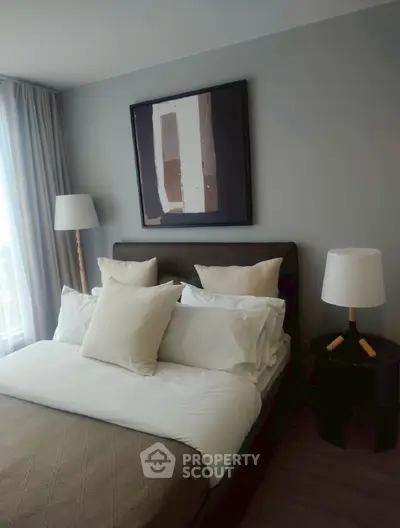Cozy bedroom with modern decor and natural light, featuring a stylish bed and elegant artwork.