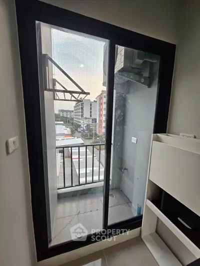 Modern apartment balcony with sliding glass door and urban view, perfect for city living.