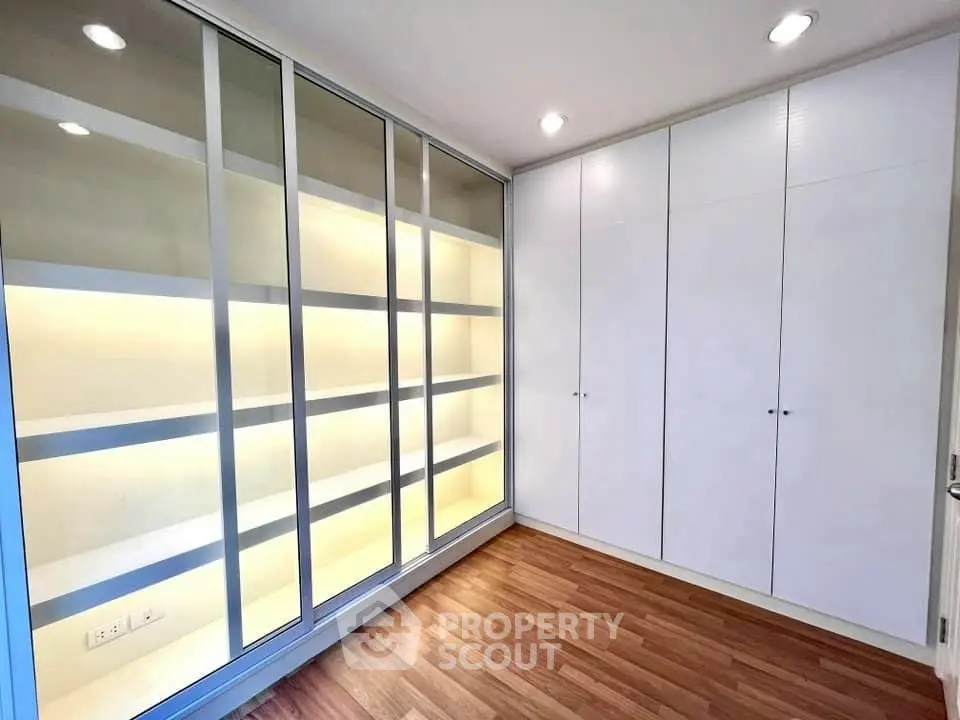 Spacious storage room with modern built-in cabinets and wooden flooring.