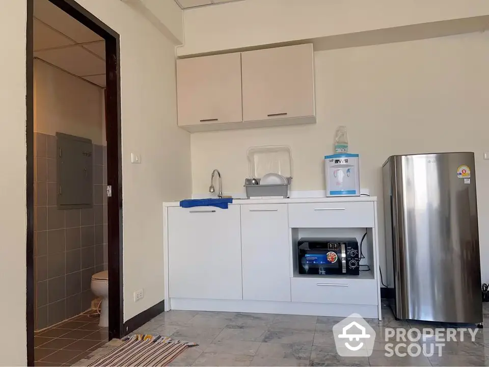 Compact kitchen with modern appliances and adjacent bathroom in cozy apartment.