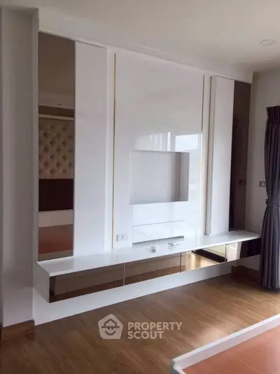 Modern minimalist living room with sleek built-in storage and elegant wood flooring.