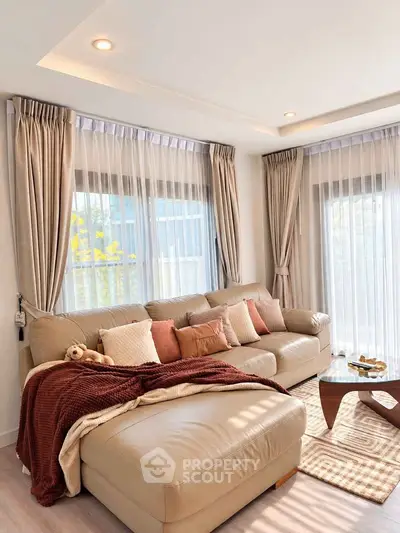 Luxurious living room with plush leather sofa and elegant curtains, bathed in natural light.