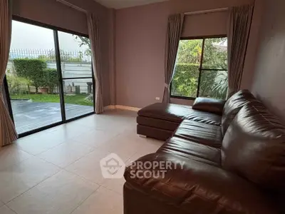Spacious living room with leather sofa and garden view, perfect for relaxation and entertaining.