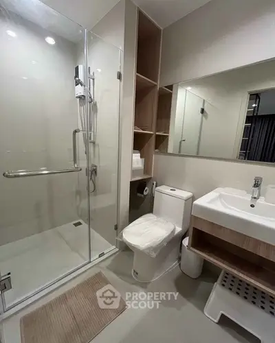 Modern bathroom with glass shower, sleek vanity, and contemporary fixtures.